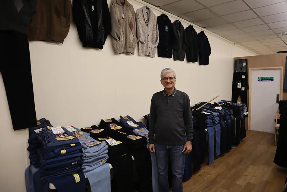 A person standing in front of a row of clothes