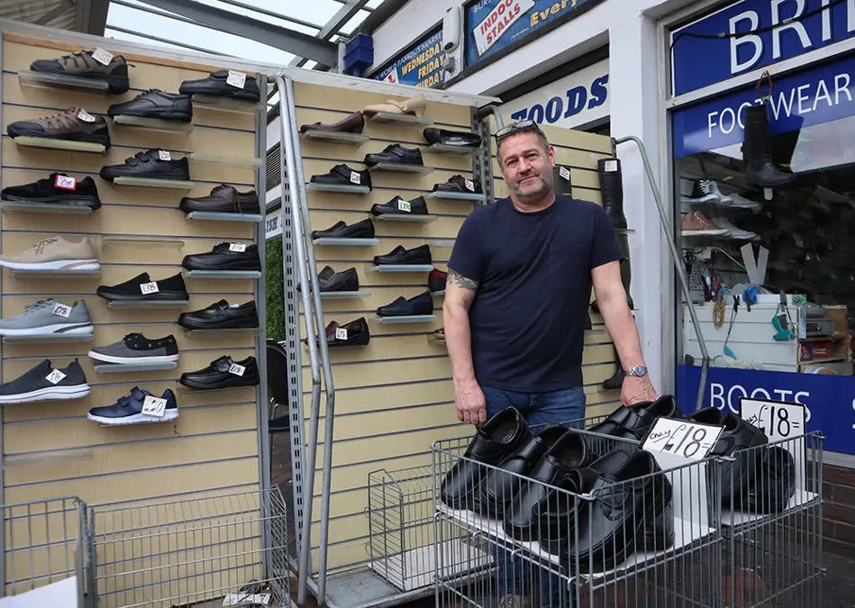 A person standing in front of a rack of shoes, trainers and sandals