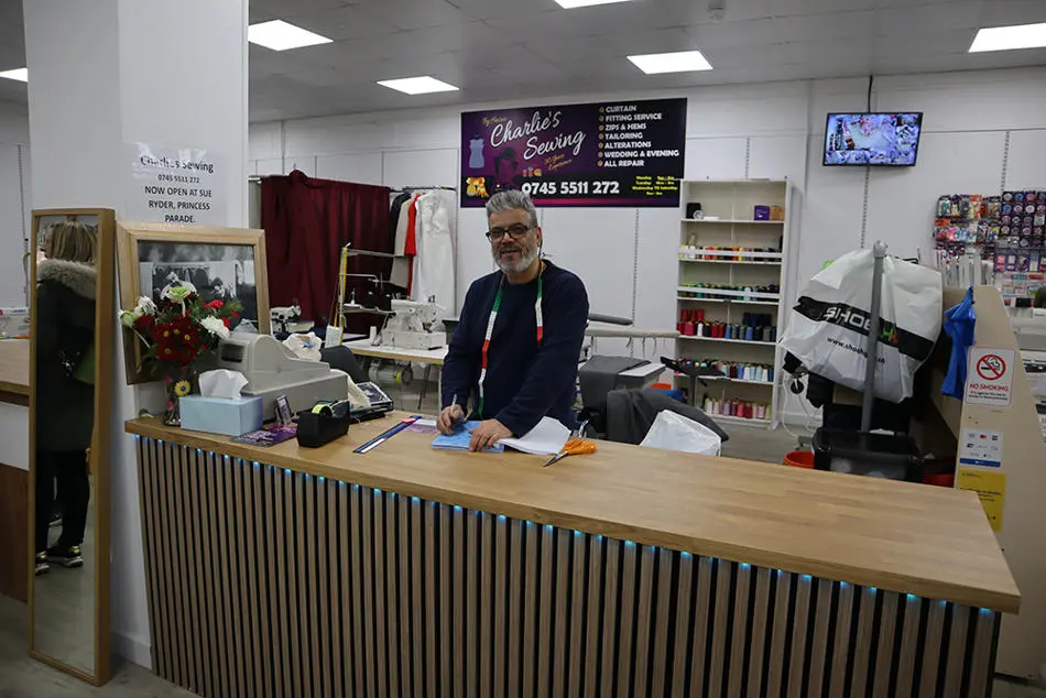 A person standing behind a counter holding a pen and paper