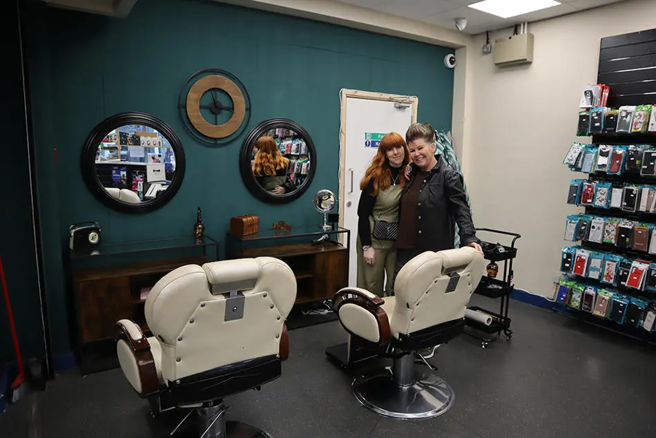Two people standing in front of a barber's chair