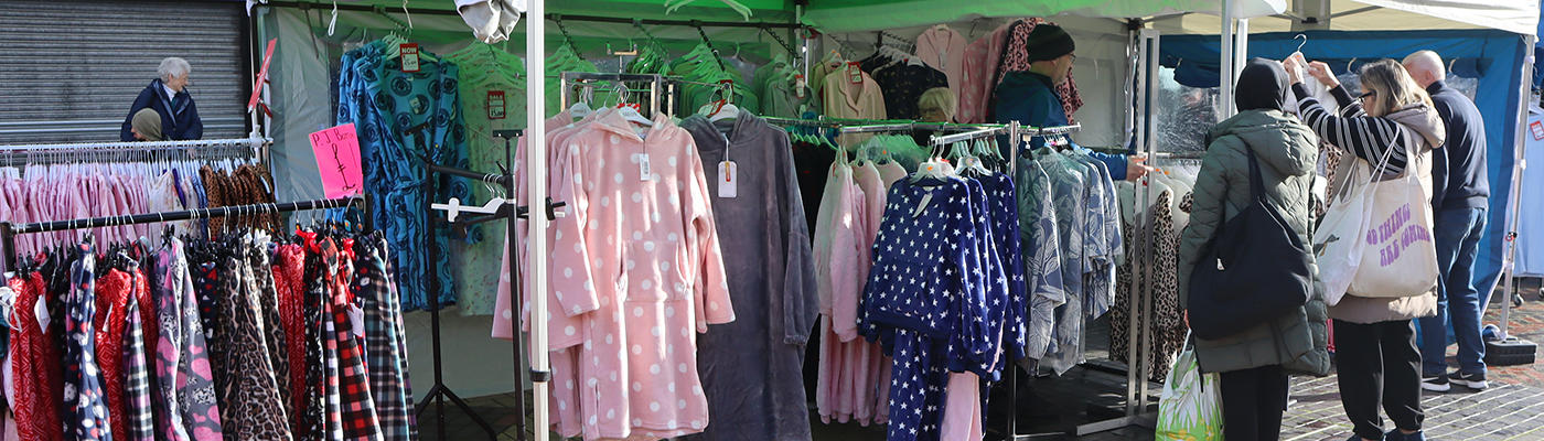 Racks of dressing gowns and pyjamas under a covered market stall 