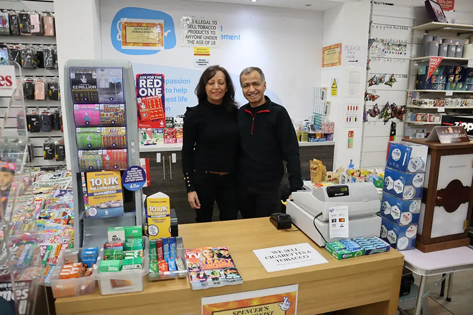 Two people standing behind a shop counter