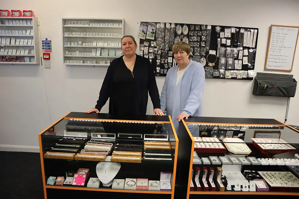 Two people standing behind a display case containing lots of jewellery