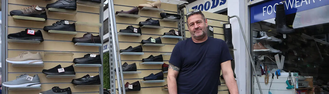 A person standing in front of a rack of shoes, trainers and sandals