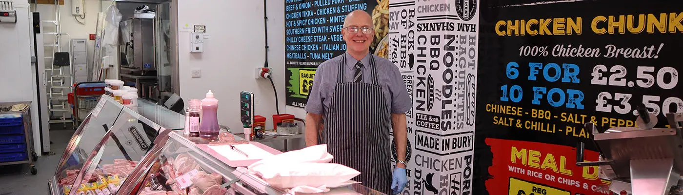 Person standing behind a food counter wearing an apron