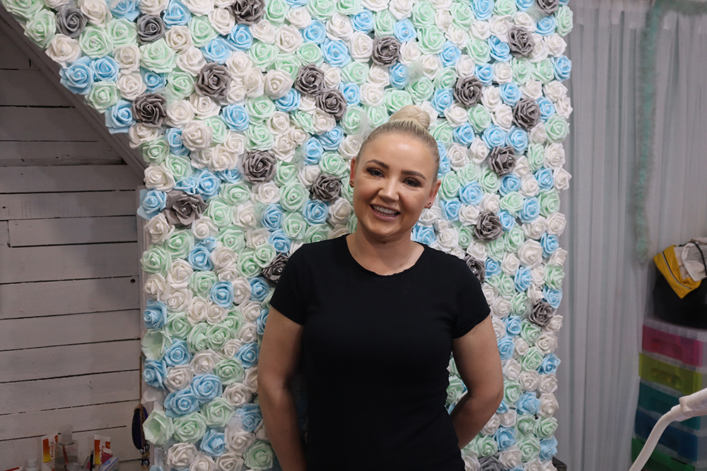 A person standing in front of a wall of artificial flowers