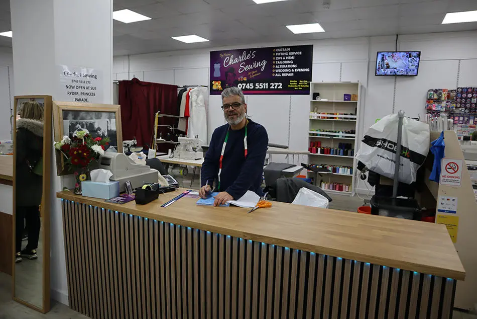 A person standing behind a counter holding a pen and paper
