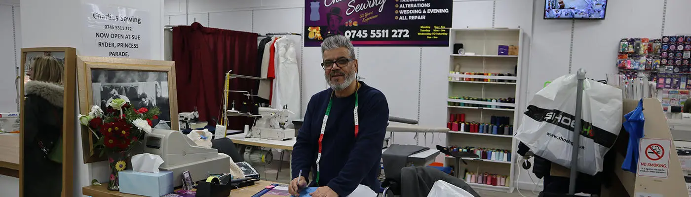 A person standing behind a counter holding a pen and paper