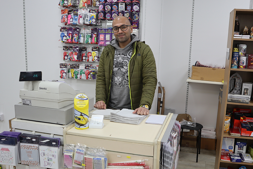 A person standing in front of a rows of badges and packets of balloons