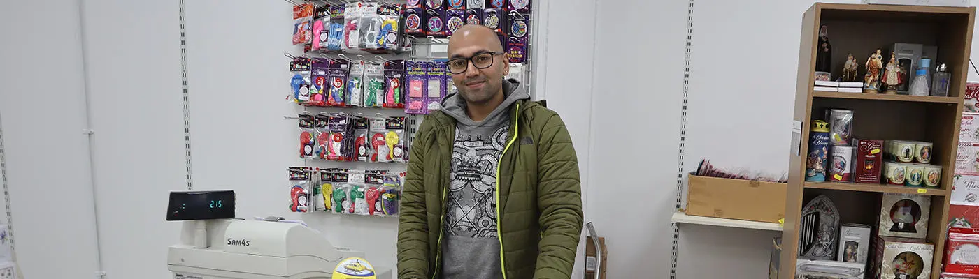 A person standing in front of a rows of badges and packets of balloons