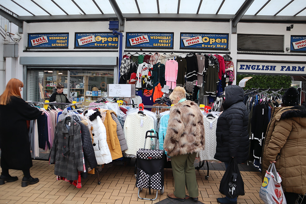 People looking at clothes on rails outside a shop