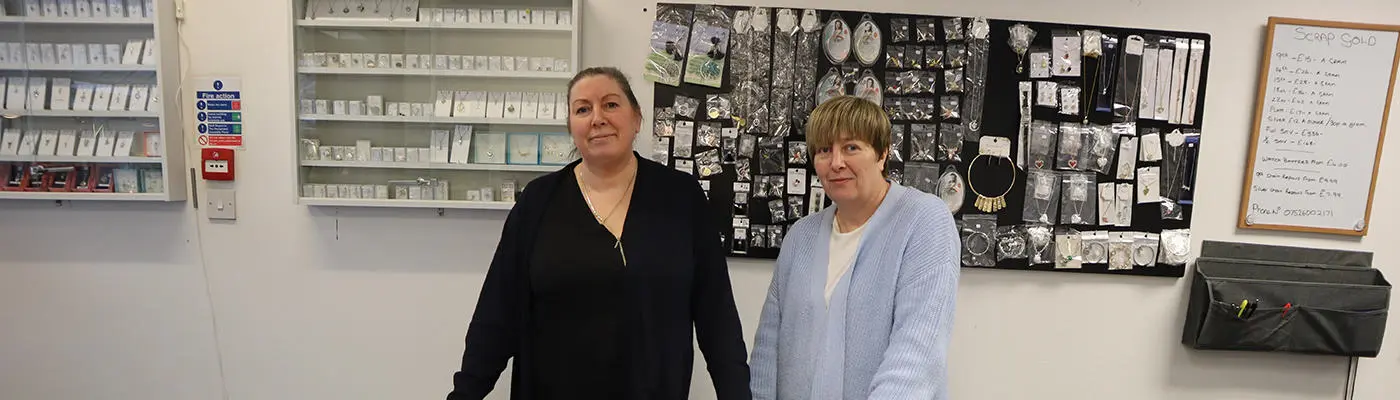 Two people standing in front of a rows of jewellery